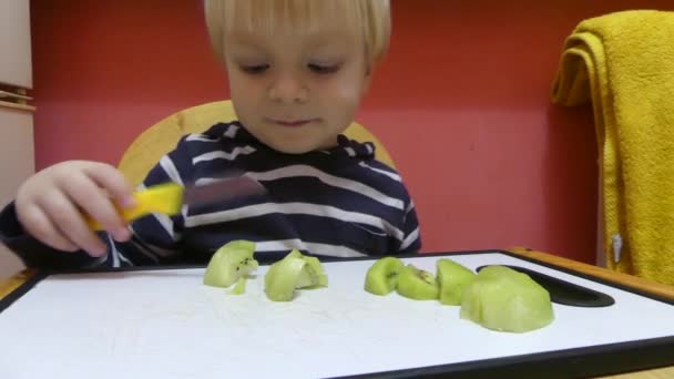 子供はナイフで果物を切っています 少年は 基板のナイフで果物をカットします — ストック動画