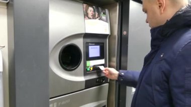 Kopenhag, Danimarka-Mart 2019: bir adam otomatik bir alıcı şişe boş kabinleri koyar. Ters otomat geri dönüşüm makinesi. Nakit dağıtır geri dönüşüm makinesi. Adam el makineye plastik şişe koyar