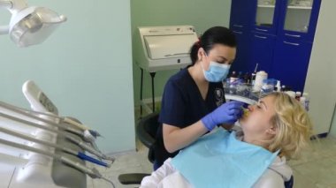 Kiev, Ukrayna-Nisan 2019: kız dişçi resepsiyonunda. Dişçi diş hekimliği ofisinde hastaya diş davranır. Diş hekimi klinikte hasta davranır.
