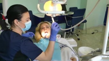 Kiev, Ukrayna-Nisan 2019: kız dişçi resepsiyonunda. Dişçi diş hekimliği ofisinde hastaya diş davranır. Diş hekimi klinikte hasta davranır.