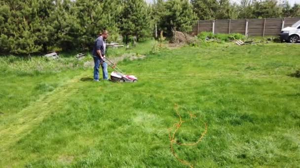 Un homme tond la pelouse à la datcha. La tondeuse coupe l'herbe à la datcha .