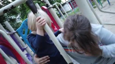 Üç yaşında bir çocuk kum havuzunda oynuyor. Rebony bahçede kumla oynuyor. Kum havuzunda çocuk oyuncakları var. Çocuk spatula ve kova.