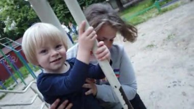 Üç yaşında bir çocuk kum havuzunda oynuyor. Rebony bahçede kumla oynuyor. Kum havuzunda çocuk oyuncakları var. Çocuk spatula ve kova.