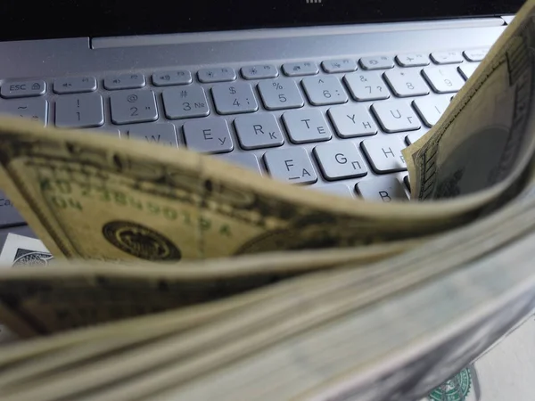Stos dolarów amerykańskich na tle klawiatury laptopa. Wiele o — Zdjęcie stockowe