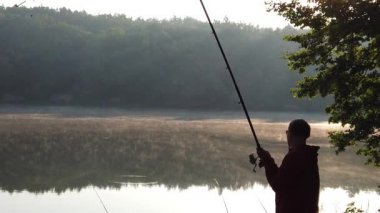 Orman gölünde balıkçılık. Bir adam balık tutmaya atıyor. Adam ormanda gölde balıklar.