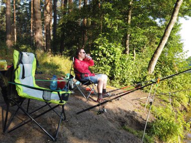 Ormanda balıkçılık yaparken sahilde balıkçılık çubukları olan bir adam ben