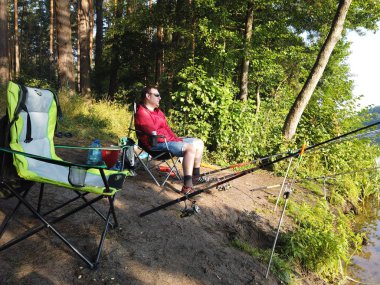 Ormanda balıkçılık yaparken sahilde balıkçılık çubukları olan bir adam ben