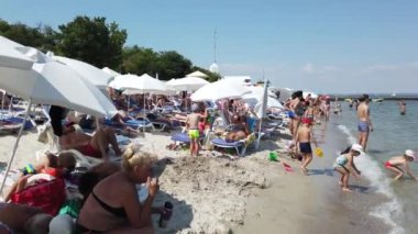 Odessa, Ukrayna, Avrupa - Temmuz 2019: İnsanlar Karadeniz sahilinde dinlenirken. Sahilde şemsiyeli şezlonglar. Dinlenen Ukrayna Devlet Başkanı Vladimir Zelensky'nin bulunduğu plajın manzarası