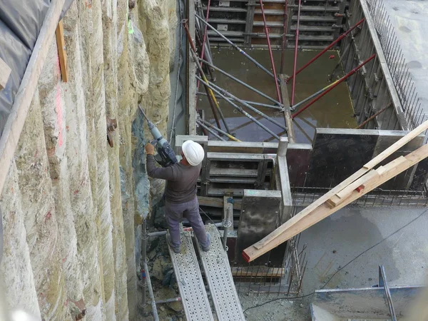 Um construtor trabalha na construção de um edifício. Trabalhador com um — Fotografia de Stock