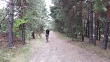 Kiev, Ukrayna, Avrupa - Ağustos 2019: Orman yolunda bisiklet sürmek. Ormanda bir bisikletçi bir yolda gidiyor. Ormanda bisiklet turu.