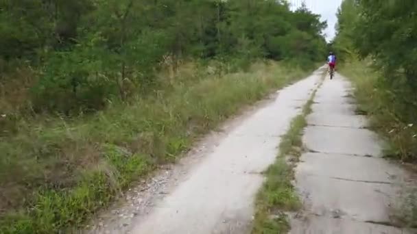 キエフ ウクライナ ヨーロッパ 8月2019 森林道路上の自転車に乗る サイクリストが森の中の道を走る 森を自転車で巡るツアー — ストック動画