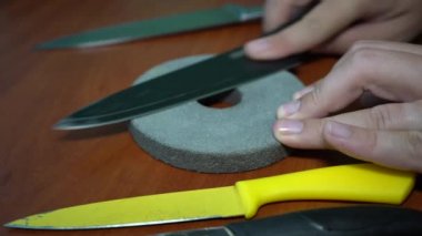 Erkeklerin elleri masa bıçaklarını keskinleştirir. Ahşap arkaplan.