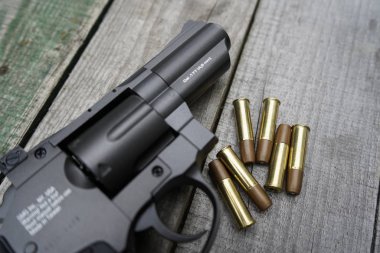 Tahta arka planda fişekleri olan hava tabancası..