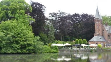 Bruges, Belçika - Mayıs 2019: Park ve Minnewater Gölü manzarası. Gölün kenarındaki kale.