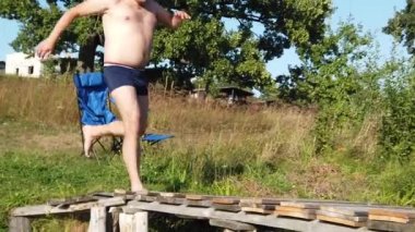 Bir adam tahta bir kaldırımdan göle atlar. Bir adam tahta bir köprüden göle dalıyor..