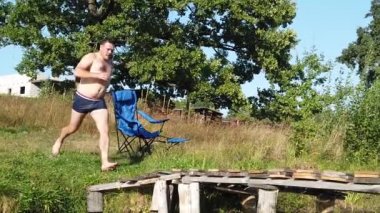 Bir adam tahta bir kaldırımdan göle atlar. Bir adam tahta bir köprüden göle dalıyor..