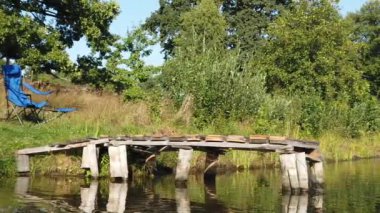 Bir adam tahta bir kaldırımdan göle atlar. Bir adam tahta bir köprüden göle dalıyor..