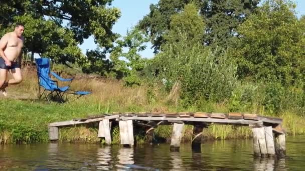 Een Man Springt Het Meer Van Een Houten Stoep Een — Stockvideo