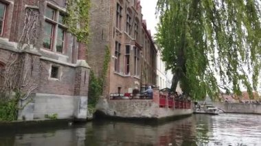 Bruges, Belçika - Mayıs 2019: Şehir merkezindeki su kanalının görünümü. Turist şehrin su kanalları üzerinde yürümek. Bir turist teknesinden görünüm.