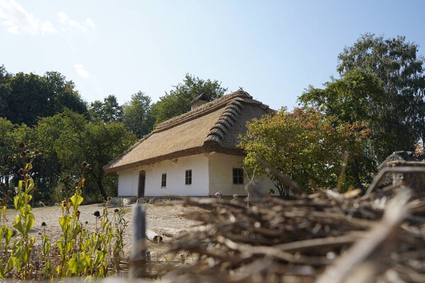 Kiev, Ukraine, Europe - September 2019: Old wooden house with a thatched roof. Old wooden house surrounded by forest. Pirogovo Museum.