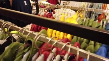 Kadın eli butikte kıyafet seçer. Bir mağazadaki askıda asılı renkli kıyafetler.