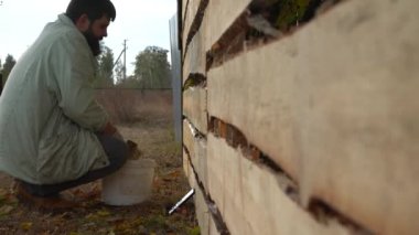 Sakallı adam yeni bir ahşap çit boyuyor. Yeni bir ahşap çit işleniyor. Yeni bir çit boyuyorum..