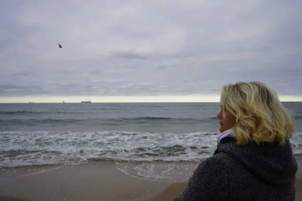 A girl looks into the distance against the backdrop of a cold se — Stock Photo, Image