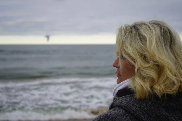 A girl looks into the distance against the backdrop of a cold se — Stock Photo, Image