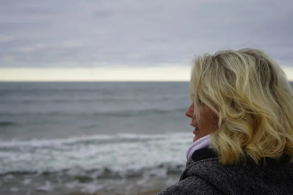 A girl looks into the distance against the backdrop of a cold se — Stock Photo, Image