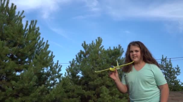 ドイツのベルリン 10月2019 女の子が松と青空を背景におもちゃの飛行機を起動します 自然を背景におもちゃの飛行機で遊ぶ女の子 — ストック動画
