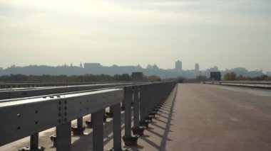 Şehrin siluetinin arka planına karşı tamamlanmamış köprü. Bitmemiş otoyol kenti. Otobanda çamurluk.