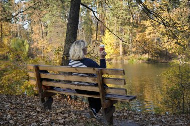 Bir kız gölün arka planında bankta oturuyor.
