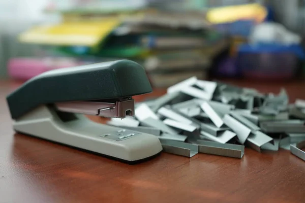 De nombreux clips pour une agrafeuse sur une table en bois. Agrafeuse avec un tas — Photo