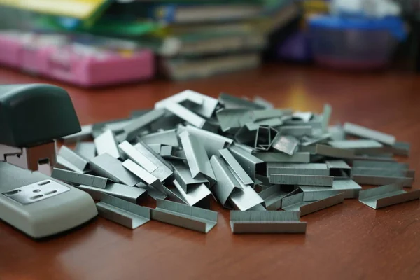 Muchos clips para una grapadora en una mesa de madera. grapadora con un montón — Foto de Stock