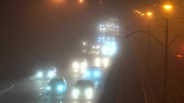 Hava durumu. Yoğun sis var. Arabalar yoğun siste hareket eder. Gece araba trafiği.
