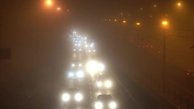 Hava durumu. Yoğun sis var. Arabalar yoğun siste hareket eder. Gece araba trafiği.