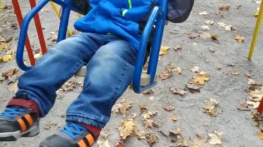 Sonbahar öğleden sonra bir çocuk salıncakta sallanıyor. Çocuk salıncağı. Dikey video.