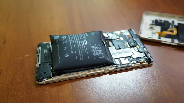  Avrupa, Kiev, Ukrayna - Haziran 2020: şişmiş akıllı telefon bataryası. Bozuk pilli, hasarlı bir akıllı telefon. Ahşap bir arka planda hasarlı telefon.