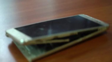Şişmiş akıllı telefon pili. Bozuk pilli, hasarlı bir akıllı telefon. Ahşap bir arka planda hasarlı telefon.