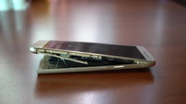 Şişmiş akıllı telefon pili. Bozuk pilli, hasarlı bir akıllı telefon. Ahşap bir arka planda hasarlı telefon.