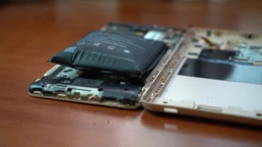 Şişmiş akıllı telefon pili. Bozuk pilli, hasarlı bir akıllı telefon. Ahşap bir arka planda hasarlı telefon.