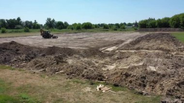 Avrupa, Zolotonosha, Çerkasya Bölgesi - Ağustos 2020: Stadyumun inşaatı. Traktör stadyumun inşaatı için alanı yerle bir ediyor. Hava görünümü.