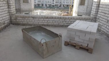 Bitmemiş ev inşaatı. İnşaat alanının arka planında beyaz tuğla var. İnşaat manzarası içeriden. Binanın iç onarım çalışmaları..