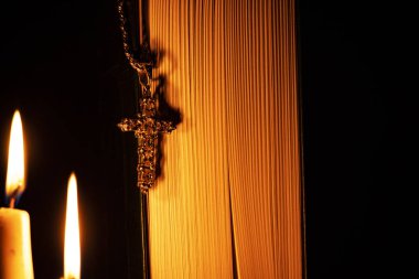 karanlık bir odada kilise mumların arka planda İncil asılı gümüş haç