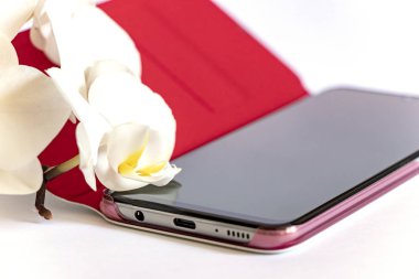 Beyaz orkide beyaz arka planda dokunmatik telefonda yatıyor