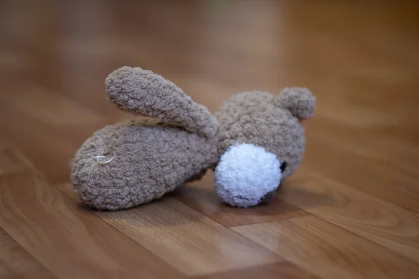 A teddy bear with a torn paw after playing with a child lies on the floor in a children\'s room