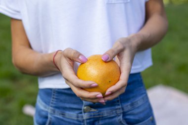 olgun bir greyfurt tutan genç kız