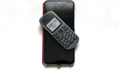 Farklı nesillerden iki cep telefonu izole bir arkaplanda dokunup düğmeye basar