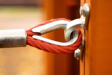 Metal bir direğe bağlanmış kırmızı halatla sokakta metal parantez var.