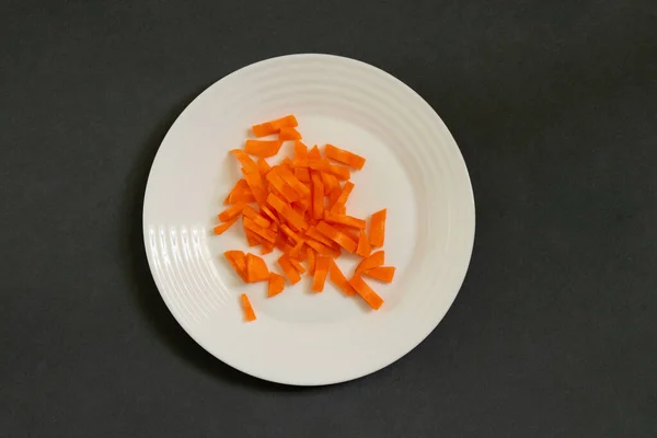 Chopped carrots julienne on a plate on a dark gray background — Stock Photo, Image